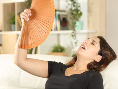 Girl suffering heat stroke fanning on a sofa / Foto: Antonioguillem Getty Images