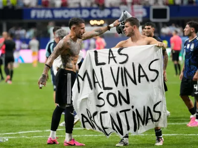 Argentina's Giovani Lo Celso holds a banner with the words "The Malvinas are Argentine", referring to the Falkland Islands, while teammate Argentina's Nicolas Otamendi gestures to him, at the end of the World Cup semifinal soccer match between England and Argentina in Atlanta, Wednesday, July 15, 2026. (AP Photo/Rebecca Blackwell)
