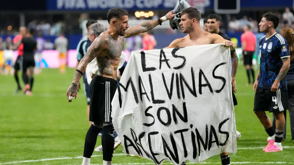 Argentina's Giovani Lo Celso holds a banner with the words "The Malvinas are Argentine", referring to the Falkland Islands, while teammate Argentina's Nicolas Otamendi gestures to him, at the end of the World Cup semifinal soccer match between England and Argentina in Atlanta, Wednesday, July 15, 2026. (AP Photo/Rebecca Blackwell)