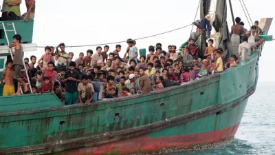 Migrants sit on their boat as they wait to be rescued by Acehnese fishermen on the sea off East Aceh, Indonesia, Wednesday, May 20, 2015. Hundreds of migrants stranded at sea for months were rescued and taken to Indonesia, officials said Wednesday, the latest in a stream of Rohingya and Bangladeshi migrants to reach shore in a growing crisis confronting Southeast Asia. (AP Photo/S. Yulinnas)