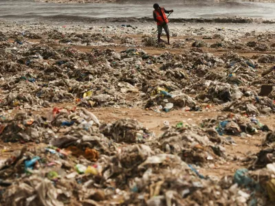 A worker cleans up garbage washed onto a beach after high tide in Mumbai, India, July 15, 2026. REUTERS/Francis Mascarenhas