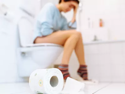 silhouette of woman sitting on toilet on blurred background. Sick, unhealthy woman, teenager, suffering from diarrhea, constipation and cystitis in toilet. Abdominal pain during PMS. healthcare and pain concept