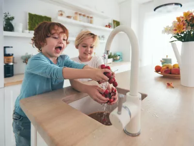 happy kids washing cherries under tap water at the kitchen