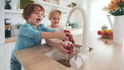happy kids washing cherries under tap water at the kitchen