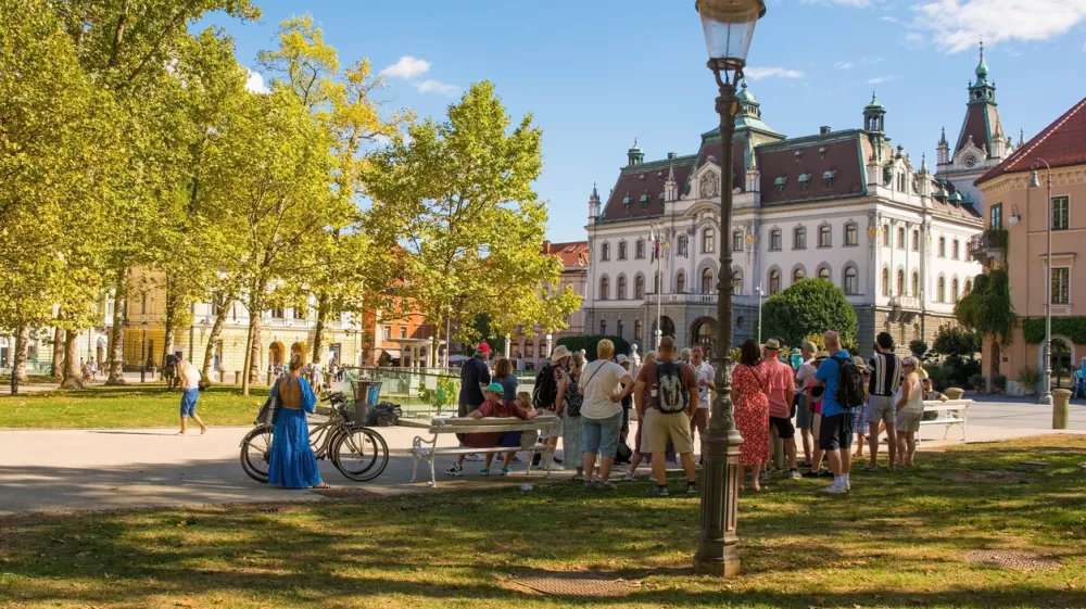 Ljubljana, Slovenia - September 4th 2022. A tour group stops to listen to their guide on a summer afternoon in Park Zvezda in the centre of Ljubljana, Slovenia
