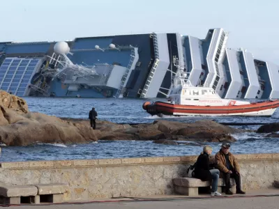 The cruise ship Costa Concordia lies on its side off the tiny Tuscan island of Giglio, Italy, Friday, Jan. 20, 2012. The 0 million Costa Concordia was carrying more than 4,200 passengers and crew when it slammed into well-marked rocks off the island of Giglio after the captain made an unauthorized diversion from his programmed route. The ship then keeled over on its side. (AP Photo/Gregorio Borgia)