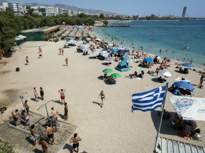 People gather at a beach as temperatures reached 39 Celsius degrees, (102.2 Fahrenheit), at Alimos suburb, south of Athens, Greece, on Sunday July 19, 2026. (AP Photo/Yorgos Karahalis)