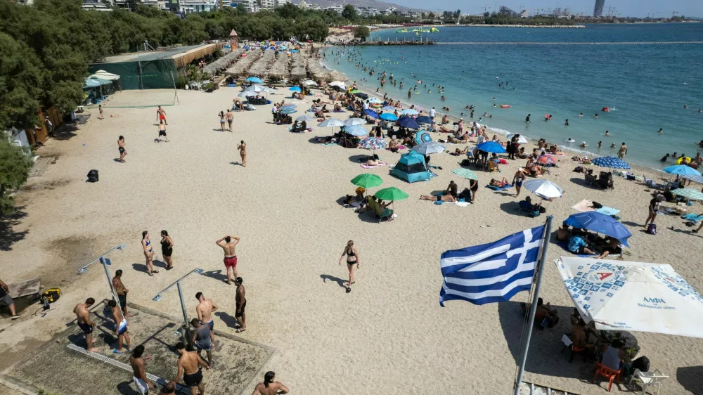 People gather at a beach as temperatures reached 39 Celsius degrees, (102.2 Fahrenheit), at Alimos suburb, south of Athens, Greece, on Sunday July 19, 2026. (AP Photo/Yorgos Karahalis)