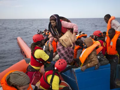 FILE- In this Friday, Feb. 3, 2017 file photo, migrants and refugees are assisted by members of the Spanish NGO Proactiva Open Arms, as they crowd on board of a wooden boat sailing out of control in the Mediterranean Sea about 21 miles north of Sabratha, Libya. Europeans have made a wrong, and dangerous, turn on the Mediterranean as they try to slow the ever-growing number of migrants crossing the sea by looking for help from Libya, a country in chaos that is the jumping-off point for the hazardous journey, Amnesty International said in a report released Thursday, July 6, 2017. (AP Photo/Emilio Morenatti, File)