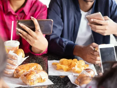 Group of unrecognizable people busy on mobile while having snacks together at restaurant - Concept of millennials having junk food, phone addiction, social media sharing and connection / Foto: Lakshmiprasad S Getty Images