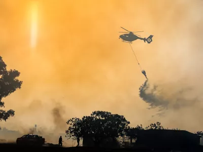 Firefighters use a helicopter to combat wildfires in Rome on Tuesday, July 21, 2026, after a fire broke out that, due to strong winds, quickly spread throughout the Acquafredda Nature Reserve. (Francesco Benvenuti/LaPresse via AP)