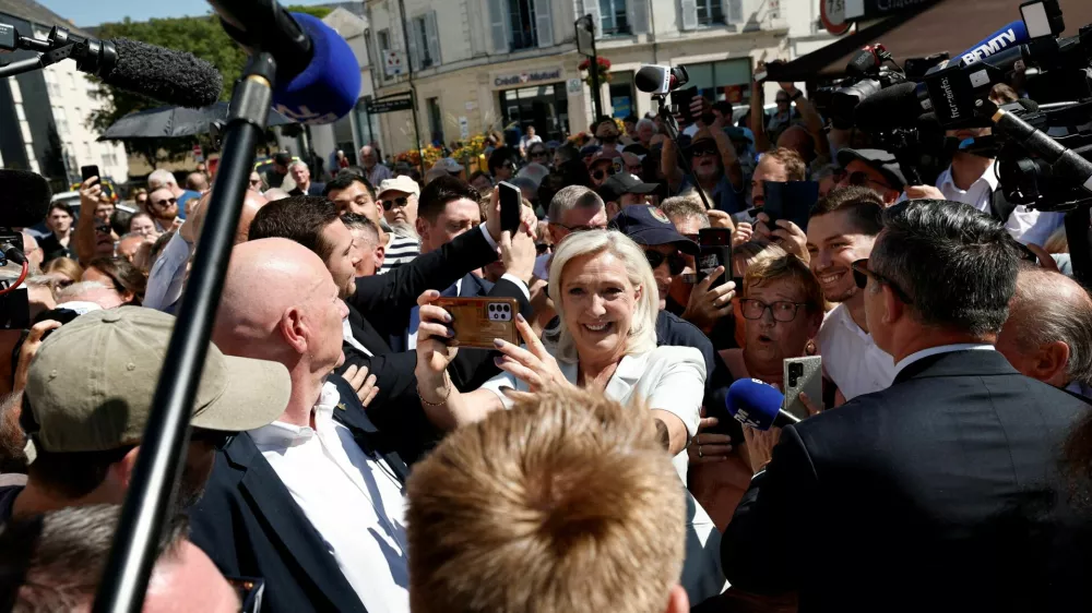 FILE PHOTO: French far-right leader Marine Le Pen and Jordan Bardella, president of the French far-right Rassemblement National (National Rally - RN) political party, make selfies with supporters surrounded by journalists in La Fleche, in the Sarthe department, France, July 8, 2026. REUTERS/Benoit Tessier/File Photo