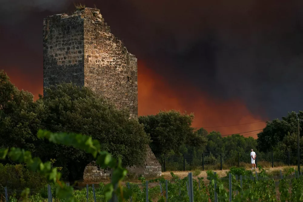 A man watches smoke drift near a ruin in the village of Cotignac, in the Var department, France, following a wildfire, July 21, 2026. REUTERS/Manon Cruz   TPX IMAGES OF THE DAY
