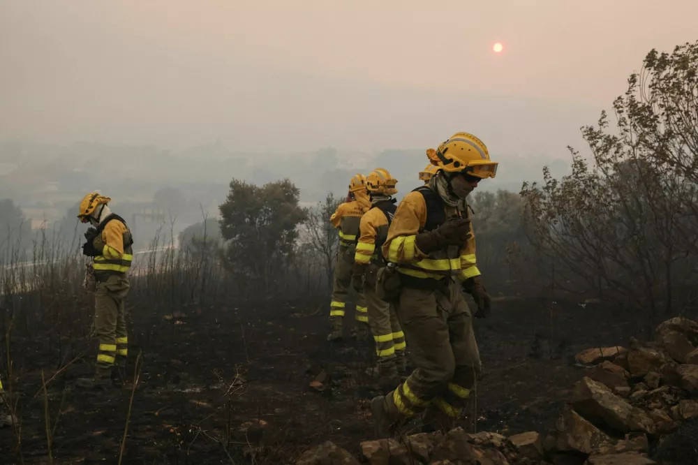 Firefighters assess the area outside the village of El Tiemblo during efforts to battle a wildfire affecting Castile y Leon province, Spain, July 24, 2026. REUTERS/Violeta Santos Moura