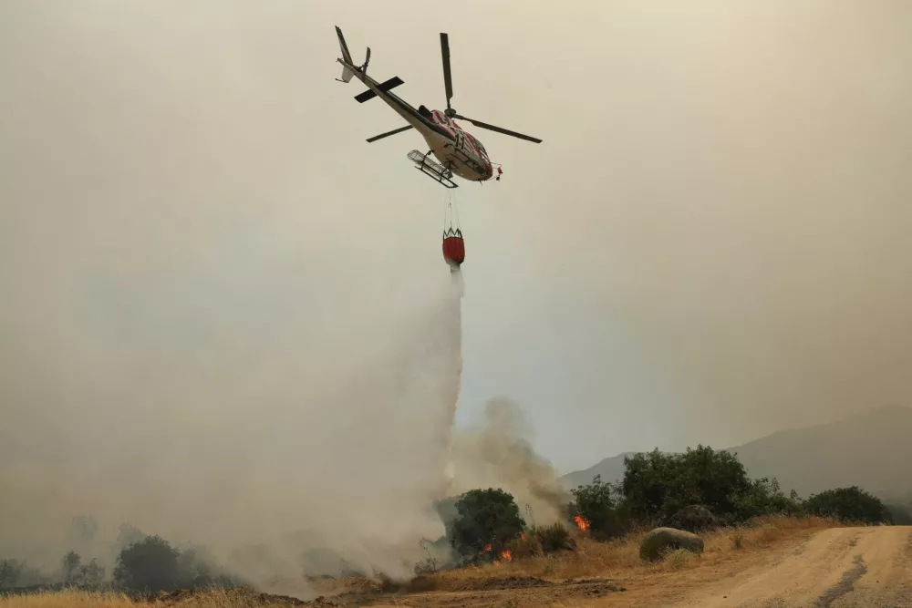 A firefighting helicopter drops water outside the village of El Tiemblo during a wildfire affecting Castilla y Leon province, Spain, July 24, 2026. REUTERS/Violeta Santos Moura