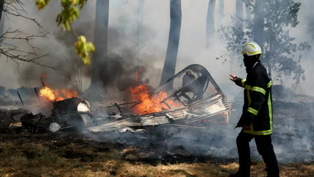 A firefighter walks next to the burning remains of a camper van during a wildfire in Lege-Cap-Ferret in the Gironde department, amid worsening drought conditions following a heatwave and water shortages across much of France, July 24, 2026. REUTERS/Stephane Mahe   TPX IMAGES OF THE DAY