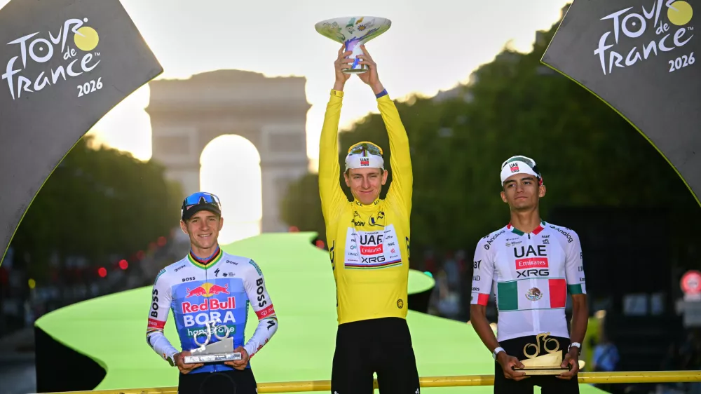 Slovenia's Tadej Pogacar, wearing the overall leader's yellow jersey, celebrates on the podium after winning the Tour de France cycling race alongside Belgium's Remco Evenepoel, second, and Mexico's Isaac Del Toro, third, in Paris, Sunday, July 26, 2026. (AP Photo/Bernard Papon/Pool Photo via AP)