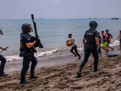 Spanish police officers respond as migrants cross from Morocco into the Spanish enclave of Ceuta, Thursday, July 30, 2026. (AP Photo/Antonio Sempere)
