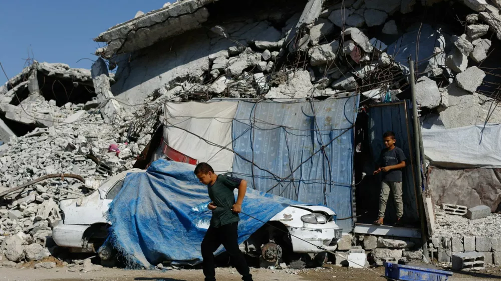 A young Palestinian pulls a wheeled cart near rubble from buildings destroyed during the war, at Jabalia refugee camp in the northern Gaza Strip, August 5, 2026. REUTERS/Mahmoud Issa