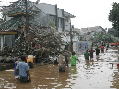 Residents wade through flood caused by burst dam in Jakarta, Indonesia, Friday, March 27, 2009. A dam burst in the outskirts of Indonesia's capital before dawn Friday, sending a flash flood into a crowded residential neighborhood, submerging hundreds of houses and killing at least 50 people, officials said.(AP Photo/Tatan Syuflana)