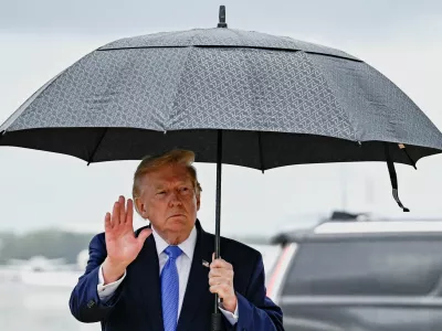 U.S. President Donald Trump gestures as he holds an umbrella after disembarking Air Force One at Joint Base Andrews, in Maryland, U.S., August 2, 2026. REUTERS/Daniel Heuer