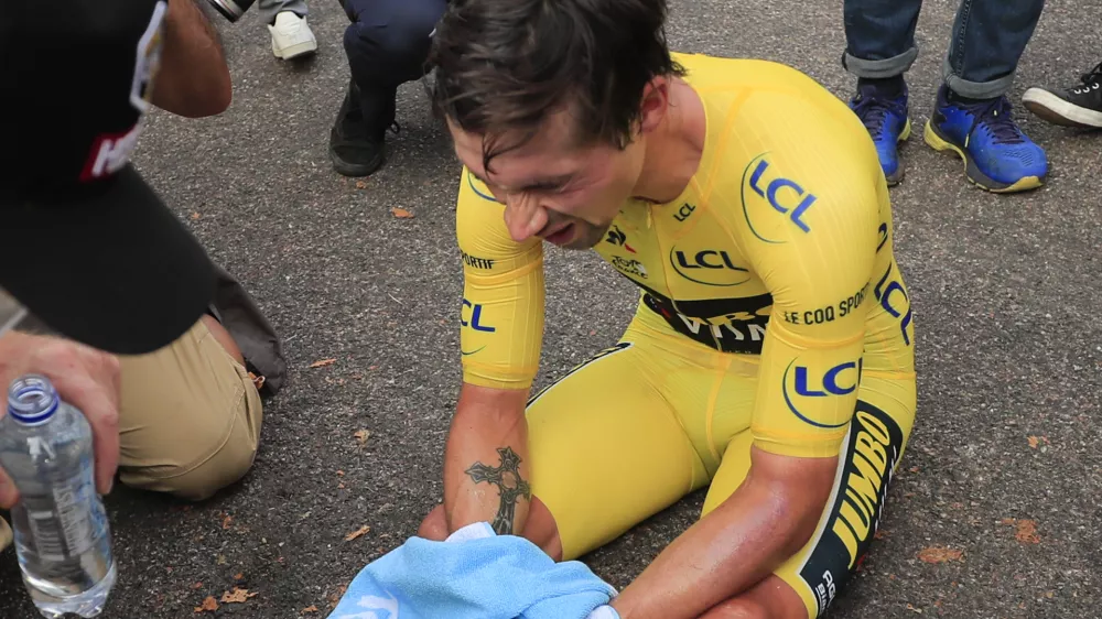 Slovenia's Primoz Roglic sits on the road after losing the overall leader's yellow jersey in stage 20 of the Tour de France cycling race, an individual time trial over 36.2 kilometers (22.5 miles), from Lure to La Planche des Belles Filles, France, Saturday, Sept. 19, 2020. (Christophe Petit-Tesson/Pool via AP)