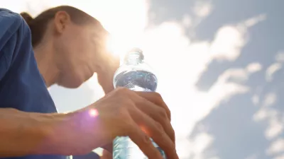 Woman drinking water in extreme summer heat wave.