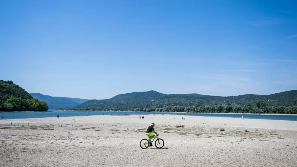 A man rides a bike on the partially dried-up bed of the Danube River in Kisoroszi, Hungary, August 1, 2026. REUTERS/Marton Monus