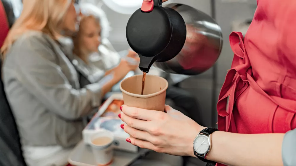 Cropped photo of stewardess holding teapot and paper cup stock photo / Foto: Yakobchukolena Getty Images/istockphoto