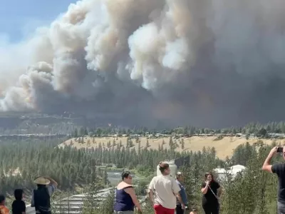 People watch as massive plumes of smoke rise from a wildfire in Spokane, U.S., August 1, 2026, in this screengrab obtained from a social media video. Tyler Vanwert/via REUTERS THIS IMAGE HAS BEEN SUPPLIED BY A THIRD PARTY. MANDATORY CREDIT. VERIFICATION: -Buildings, terrain, vegetation, road layout and solar panel match file and satellite imagery -Date and location confirmed by original file metadata
