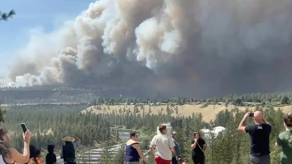 People watch as massive plumes of smoke rise from a wildfire in Spokane, U.S., August 1, 2026, in this screengrab obtained from a social media video. Tyler Vanwert/via REUTERS THIS IMAGE HAS BEEN SUPPLIED BY A THIRD PARTY. MANDATORY CREDIT. VERIFICATION: -Buildings, terrain, vegetation, road layout and solar panel match file and satellite imagery -Date and location confirmed by original file metadata