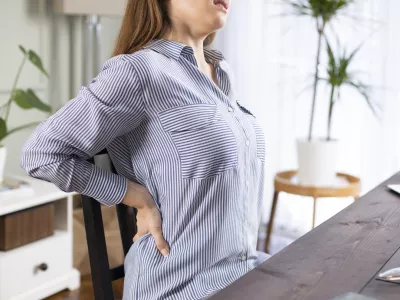 Freelancer young woman suffering with back pain while working in her office at home / Foto: Eternalcreative Getty Images/istockphoto