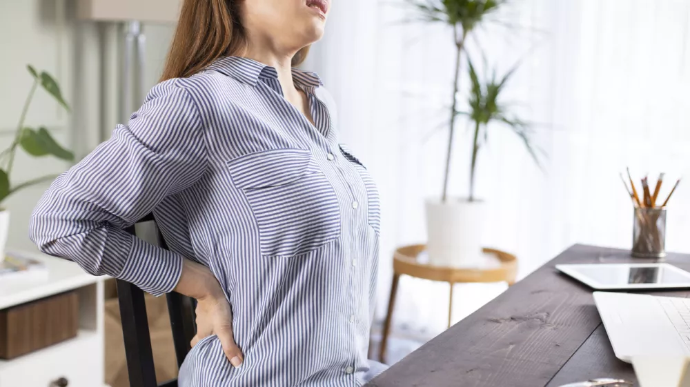 Freelancer young woman suffering with back pain while working in her office at home / Foto: Eternalcreative Getty Images/istockphoto