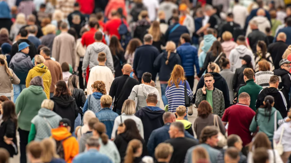 A young man is talking on the phone surrounded by a crowd during rush hour in a large metropolis. Russia, Barnaul. August 31, 2024.