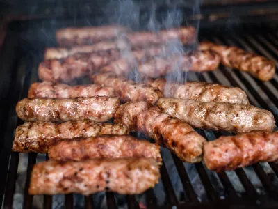 Grilling Meat on barbecue grill with hot coal. Preparing, cooking cevapcici, kebabs, country sausage on charcoal barbecue BBQ in outside fireplace. Traditional Turkish, Bosnian, Serbian, Croatian food