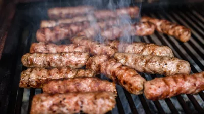Grilling Meat on barbecue grill with hot coal. Preparing, cooking cevapcici, kebabs, country sausage on charcoal barbecue BBQ in outside fireplace. Traditional Turkish, Bosnian, Serbian, Croatian food