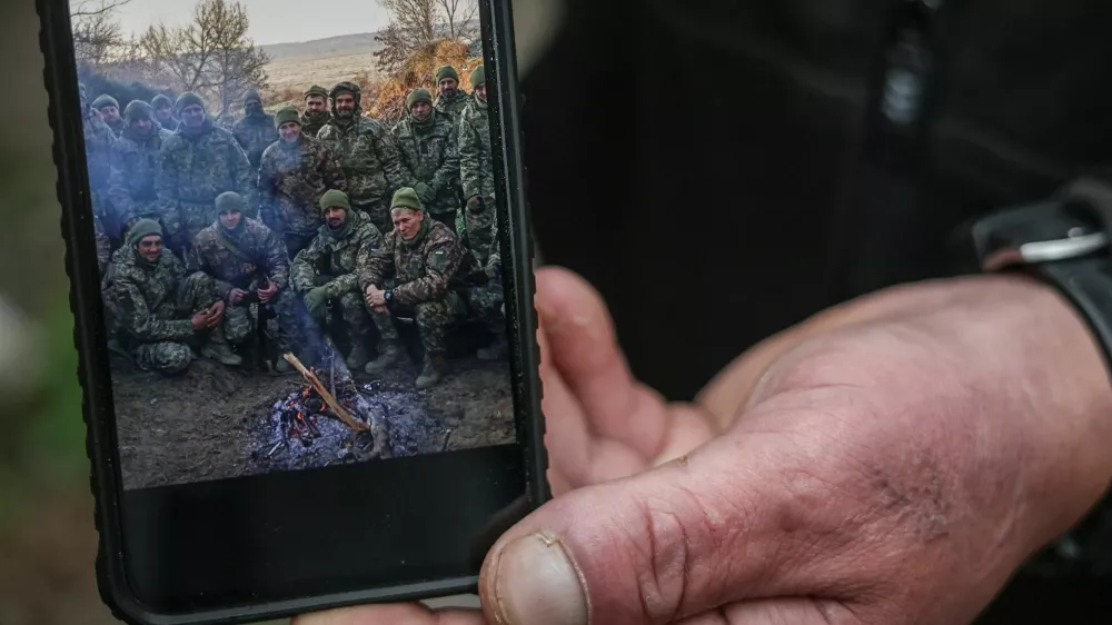 Serhii Krynitskyi, 42, a serviceman of the 24th Separate Mechanized Brigade of the Ukrainian Armed Forces, who spent 346 days at an isolated frontline position in the town of Chasiv Yar, Donetsk region, shows a photo of him with fellow soldiers in the beginning of his service in November 2024, on his first day back on duty after recovery, amid Russia's attack on Ukraine, in the frontline city of Kramatorsk in Donetsk region, Ukraine, May 27, 2026. REUTERS/Alina Smutko