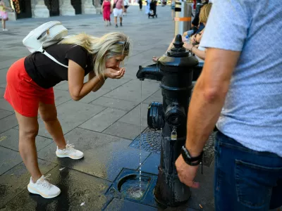 A person drinks at a public fountain near St. Stephen's Cathedral during a heatwave in Vienna, Austria, August 3, 2026. REUTERS/Elisabeth Mandl