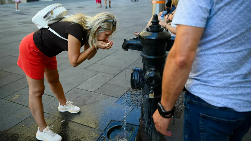 A person drinks at a public fountain near St. Stephen's Cathedral during a heatwave in Vienna, Austria, August 3, 2026. REUTERS/Elisabeth Mandl