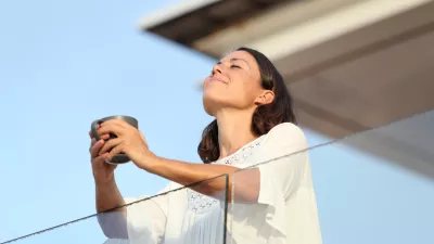 Adult woman with coffee cup breathing on a balcony