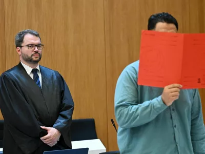 Lawyer Johann Bund and defendant Farhad N., accused of murder and other charges, arrive for his verdict in a courtroom in Munich, Germany, August 6, 2026. REUTERS/Angelika Warmuth