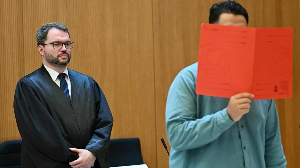 Lawyer Johann Bund and defendant Farhad N., accused of murder and other charges, arrive for his verdict in a courtroom in Munich, Germany, August 6, 2026. REUTERS/Angelika Warmuth
