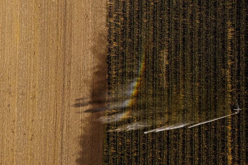 A drone view shows a rainbow forming over a irrigation sprinkler spraying water on a corn field near Engelhartstetten, Austria, August 6, 2026. REUTERS/Christian Bruna
