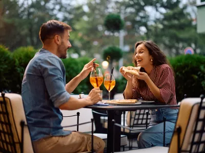Young happy couple communicating while eating pizza in restaurant.