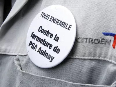 An employee of PSA Peugeot Citroen wears a badge which reads "All together against the closure of PSA Aulnay plant" during a demonstration in front of the company's headquarters during a meeting with Peugeot management and workers' representatives in Paris in this June 28, 2012 file picture. French automaker PSA Peugeot Citroen announced 8,000 job cuts and the closure of its Aulnay assembly plant as it struggles with mounting losses at its core automotive division. Peugeot said on Thursday July 12, 2012 the Aulnay plant near Paris, which employs more than 3,000 workers, will halt production in 2014 as part of a drive to reorganize output across the company's under-used French factories. REUTERS/Benoit Tessier/Files (FRANCE - Tags: BUSINESS EMPLOYMENT POLITICS TRANSPORT)