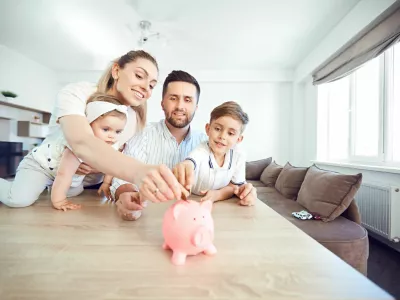 A smiling family saves money with a piggy bank. Happy family at the table in the room.