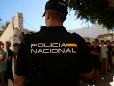 A police officer stands guard as migrant children queue outside a police station to be registered following mass crossings by migrants on foot and by sea from Morocco into Spanish territory, in Ceuta, Spain, August 6, 2026. REUTERS/Violeta Santos Moura   TPX IMAGES OF THE DAY
