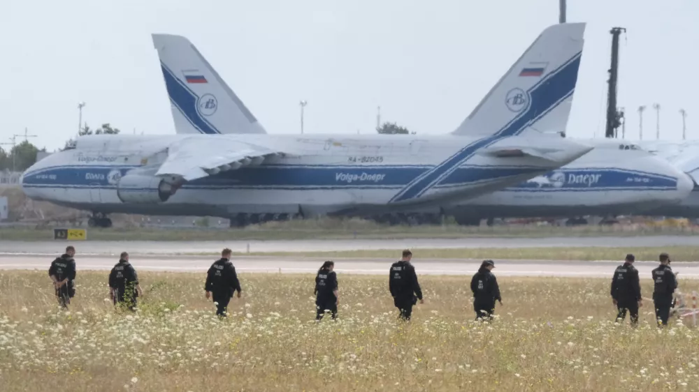 Police officers are walking across a field on the grounds of Leipzig Airport, in Schkeuditz, Germany, Friday, Aug. 7, 2026, searching for a drone that may be connected to a suspected attack. (Sebastian Willnow/dpa via AP)