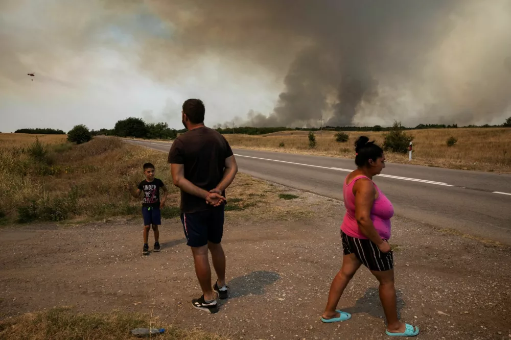 People stand by a road as wildfire burns in Deliblatska Pescara, Serbia, August 7, 2026. REUTERS/Marko Djurica