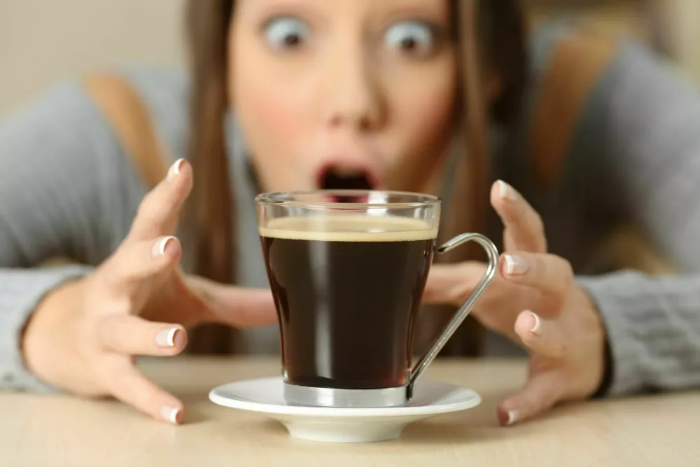 Front view portrait of an amazed woman looking at coffee cup / Foto: Antonioguillem